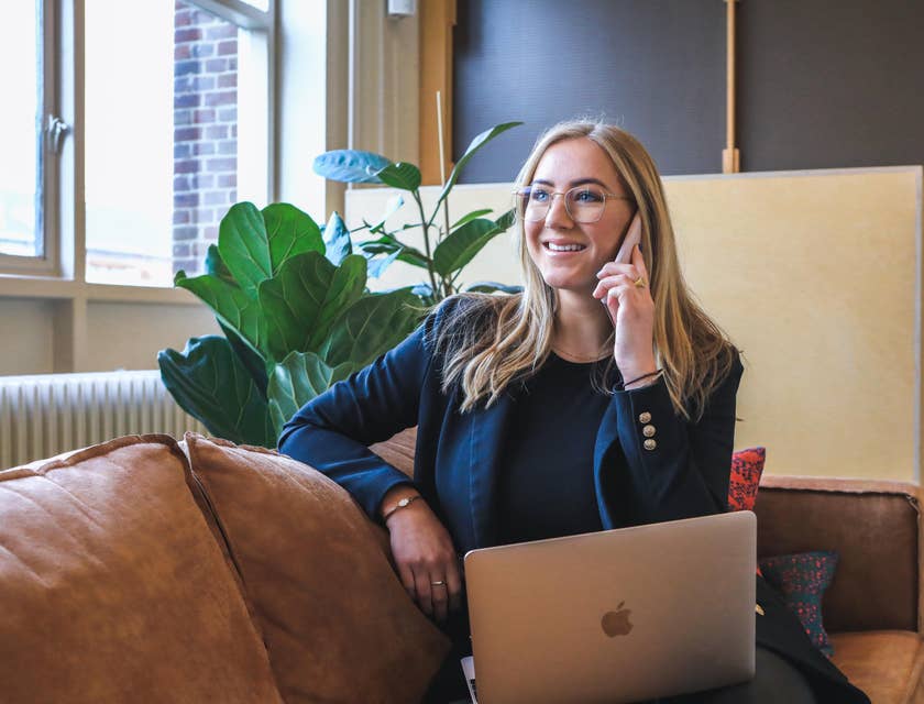 A Junior Recruiter on her laptop while talking on her mobile phone.