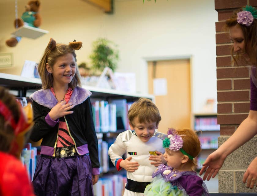Kindergarten teacher assisting one of her students while wearing their costumes