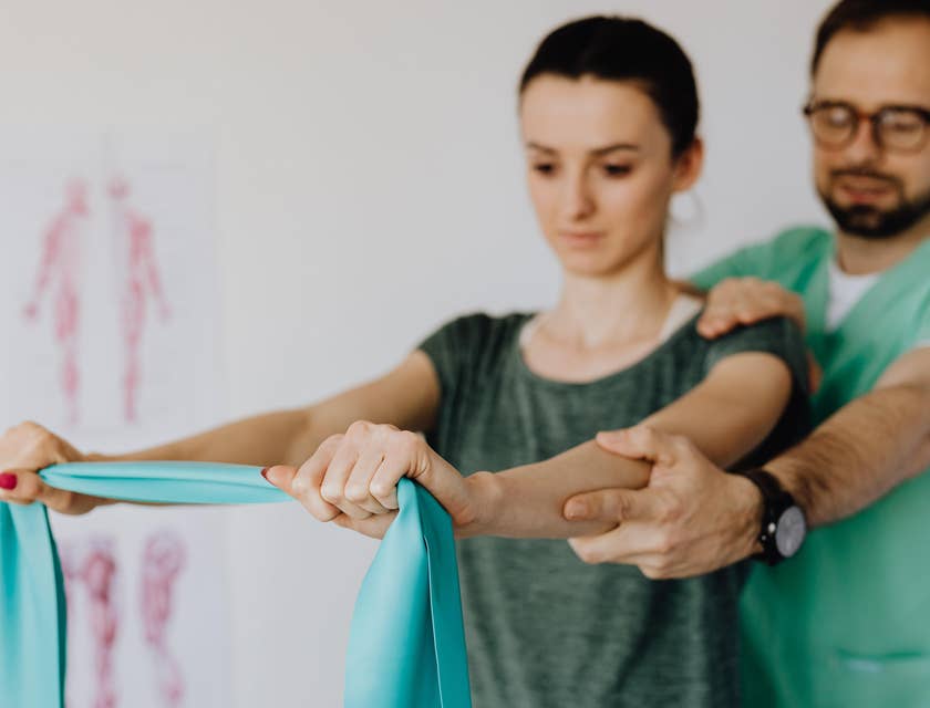 Kinesiologist monitoring patient muscle movements while using an elastic band.