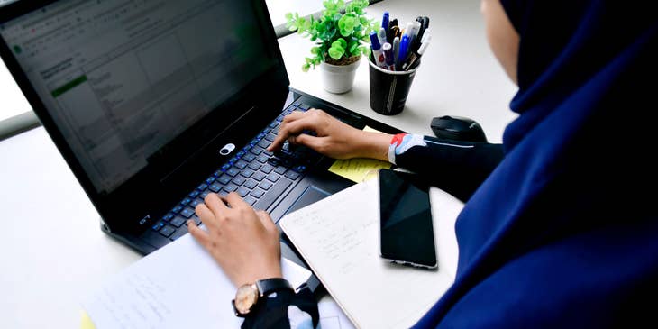 A female law clerk plotting appointments and meetings of lawyers on a shared file on her laptop.