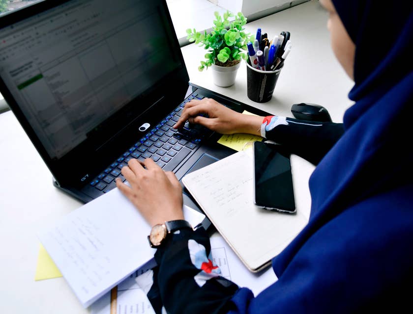 A female law clerk plotting appointments and meetings of lawyers on a shared file on her laptop.