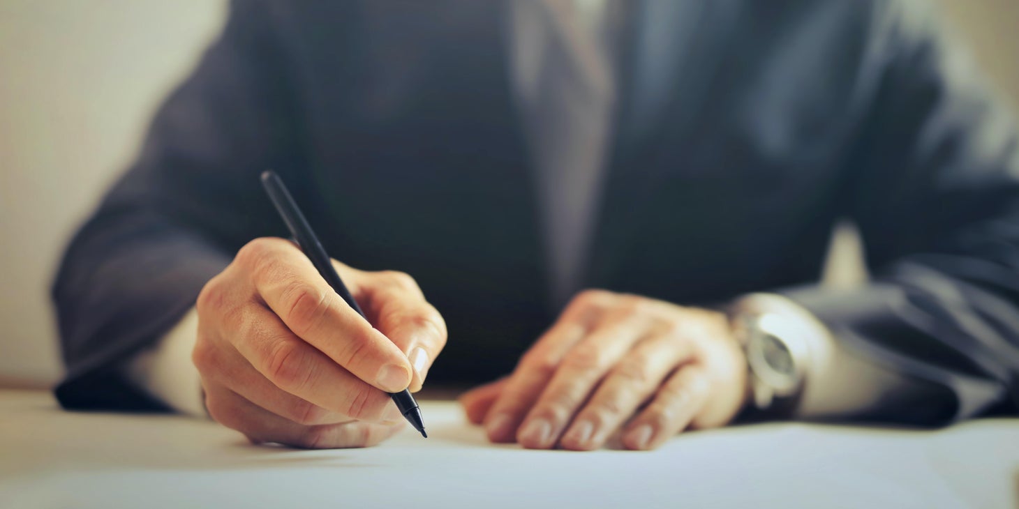 A man writing a layoff letter given to an employee.