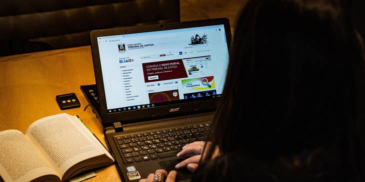 A female legal advisor researching regarding legal matters on a court of justice portal on her laptop.