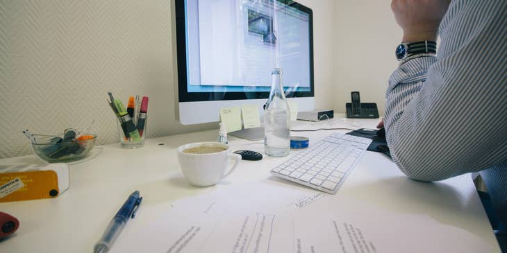 A legal assistant researching on cases on his computer while editing a hard copy of a legal document.