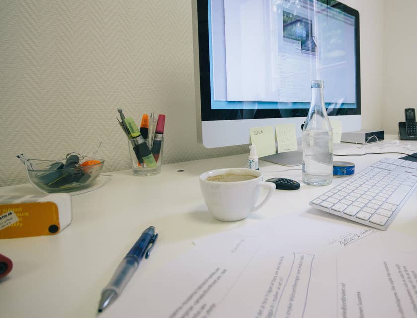A legal assistant researching on cases on his computer while editing a hard copy of a legal document.