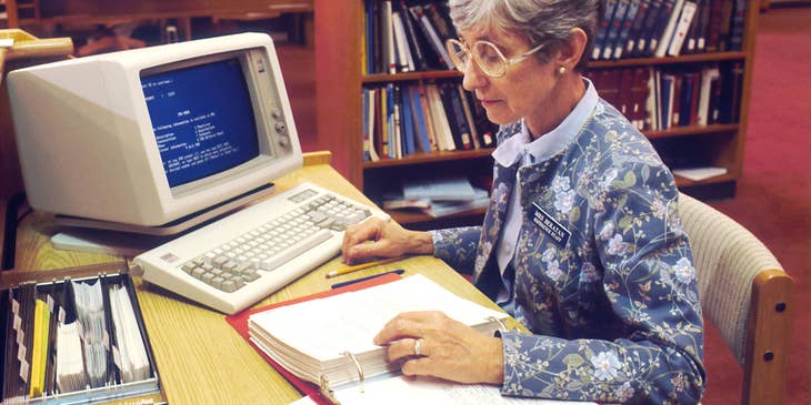 Librarian sitting at her desk reading documents.