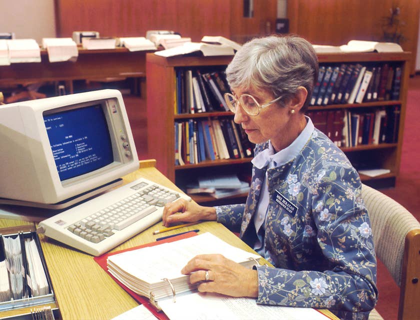 Librarian sitting at her desk reading documents.