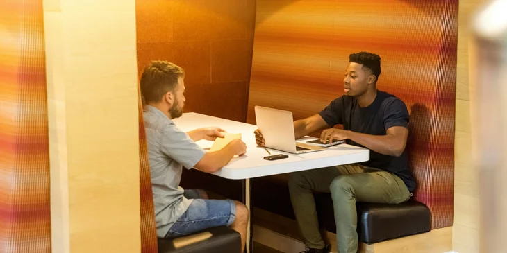 A logistics account executive on his laptop and having a conversation with a carrier agent regarding shipping arrangements.