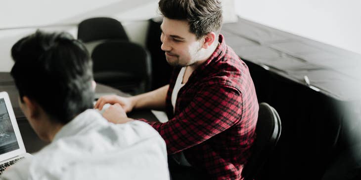A logistics account executive on his laptop and having a conversation with a carrier agent regarding shipping arrangements.