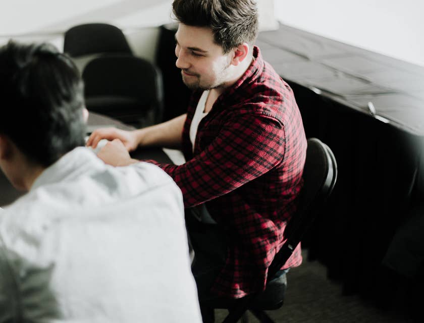 A logistics account executive on his laptop and having a conversation with a carrier agent regarding shipping arrangements.