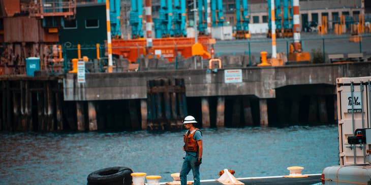 A Longshoreman using a forklift in a warehouse loading cargos to be transported to the vessels.