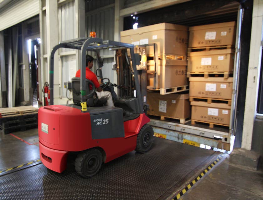 A longshoreman using a forklift in a warehouse loading cargos to be transported to the vessels.