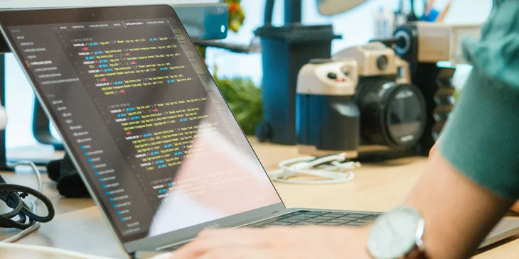 A machine learning engineer finishing his AI software program using his laptop.