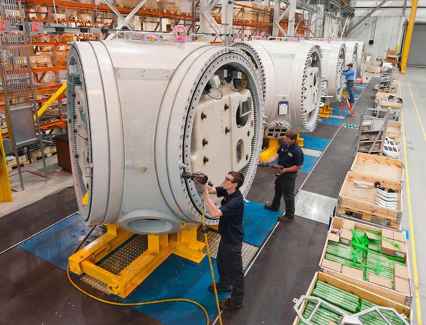 A Group of Machine Operators working on installing machines in a warehouse to be used for manufacturing.