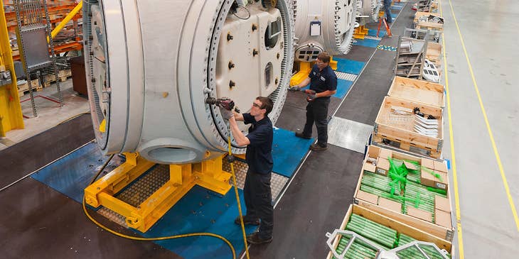 A group of machine operators working on installing machines in a warehouse to be used for manufacturing.