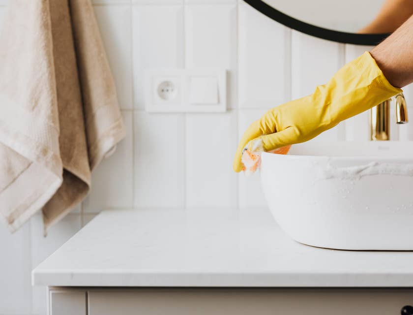 Maintenance assistant cleaning a residential bathroom sink