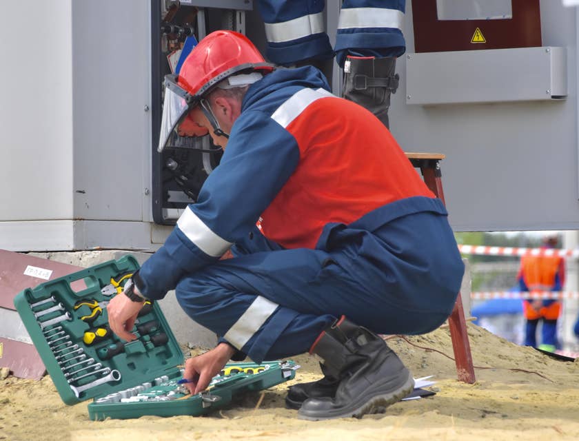 Maintenance Engineer crouching on the ground while rummaging through his toolbox for a scheduled on-site repair