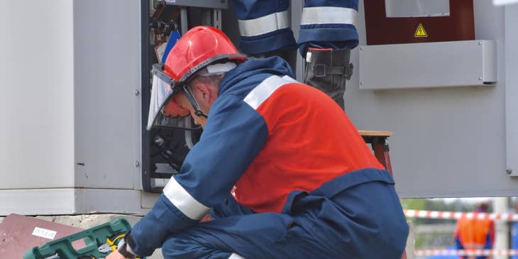 Maintenance engineer crouching on the ground while rummaging through his toolbox for a scheduled on-site repair