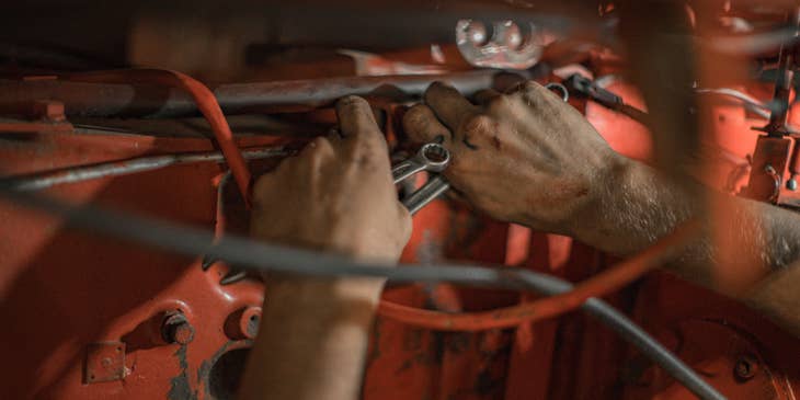 Maintenance Mechanic holding a wrench repairing a piece of equipment