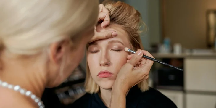 A makeup artist applying eyeshadow on a client.