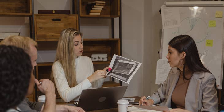 Management Analyst showing the latest productivity report to members of the executive management