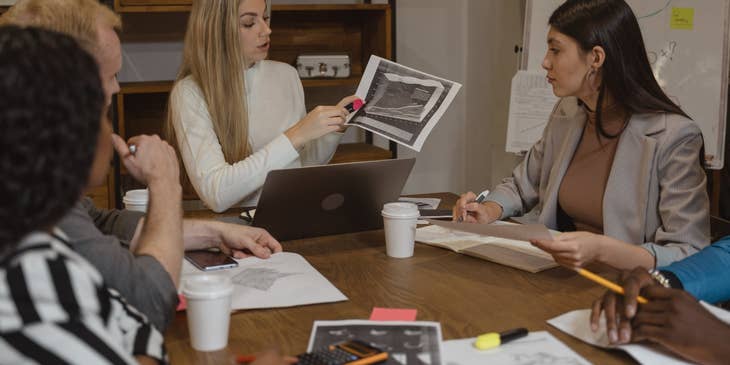 Management analyst showing the latest productivity report to members of the executive management