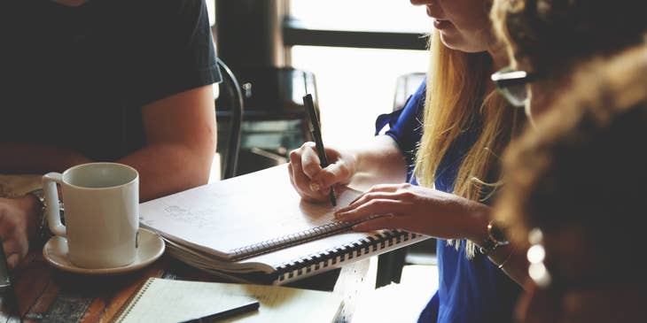 A Female Management Trainee taking down notes in a meeting.