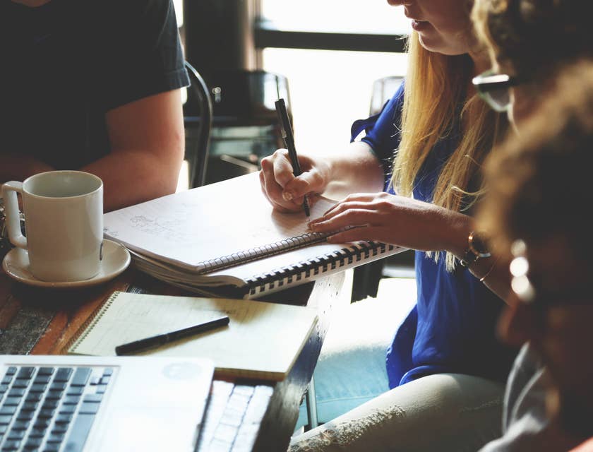 A female management trainee taking down notes in a meeting.