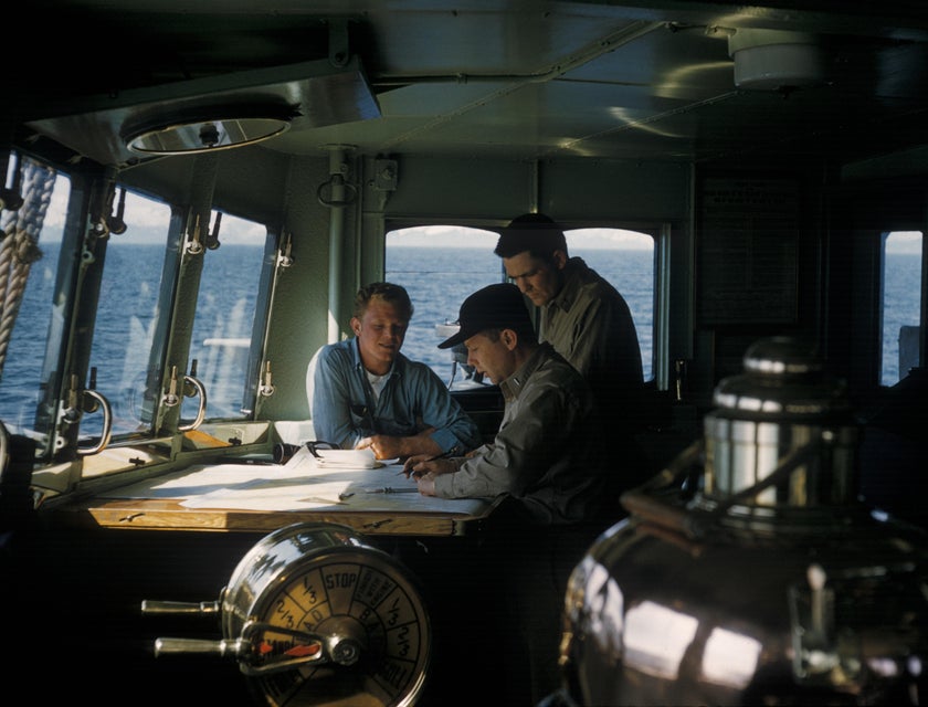 Marine Engineer discussing with his assistants the floor plan of the ship for maintenance checkup
