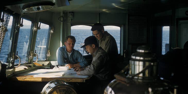 Marine engineer discussing with his assistants the floor plan of the ship for maintenance checkup