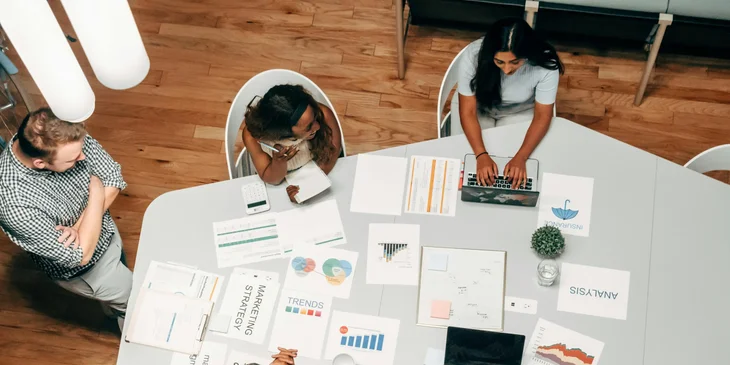 A male marketing strategist in a checkered top conducting market research with the team.