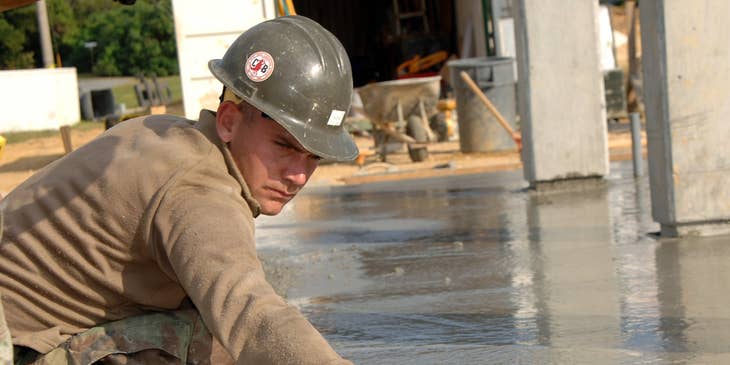 Mason leveling concrete on a construction site.