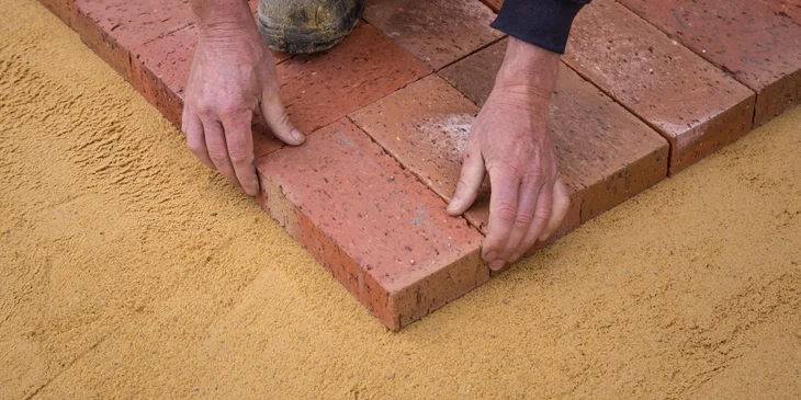 A mason laying bricks on a construction site.