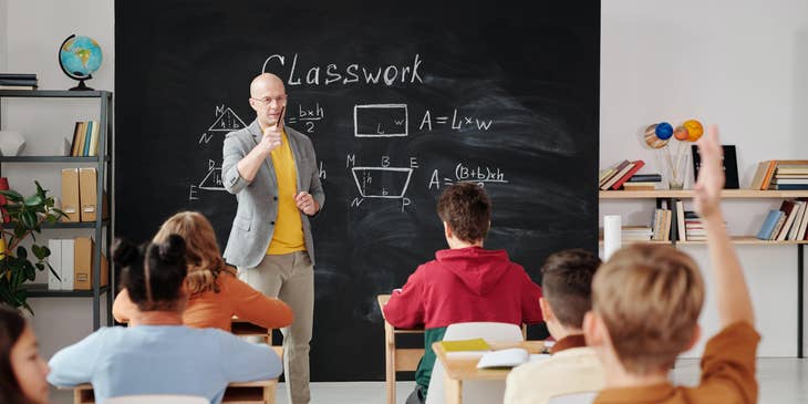 Math teacher calls the student raising his hand to answer the equation written on the board.