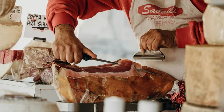 A meat packer hand cutting a meat for a client specified choice cut.