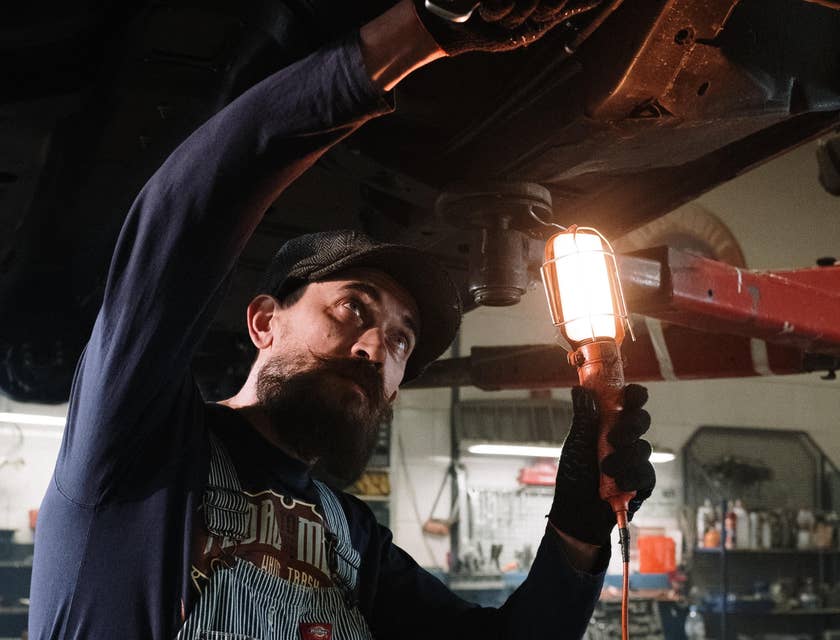 Mechanic holding a wrench and red light fixing a car.