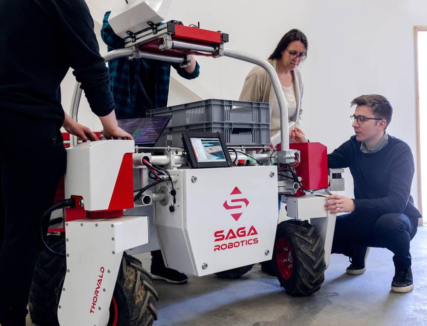 Mechatronics engineer checking an agricultural robot prior for further development while the rest of his team looks on