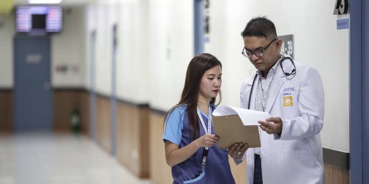 Medical support assistant showing the patient's record to the attending physician.