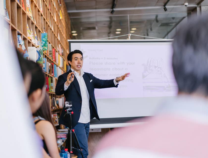 Male mentor giving a lecture beside a projector screen