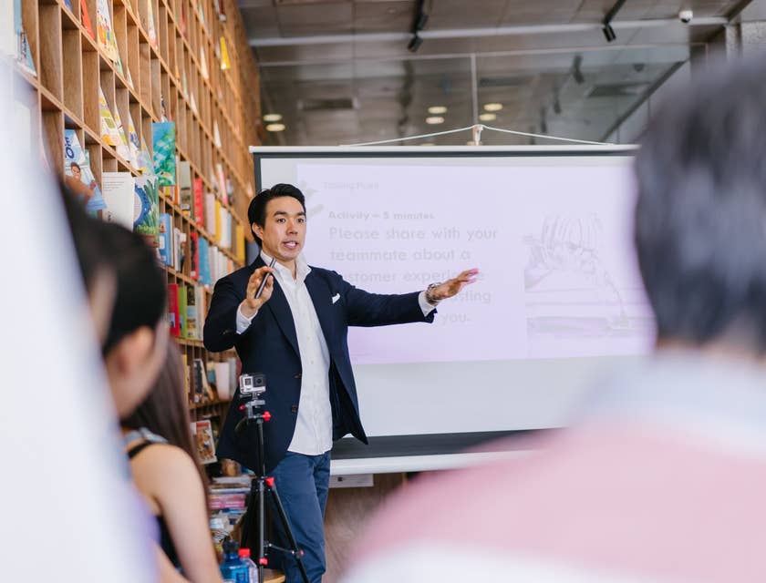 male mentor giving a lecture beside a projector screen