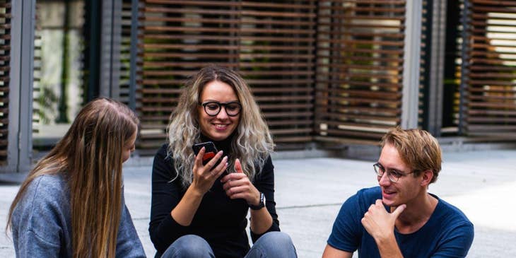 Tres empleados millennials sentados en las escaleras hablando.