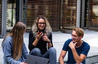 Tres empleados millennials sentados en las escaleras hablando.