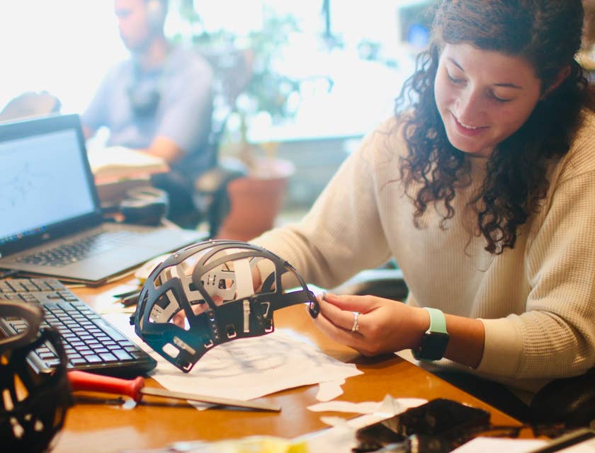 female NDT technician examining a helmet structure on her workstation with an open laptop