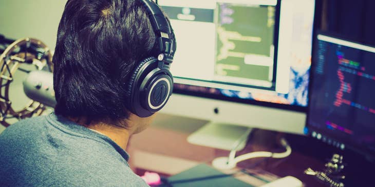 .NET Developer wearing a headset and typing a code in front of his workstation