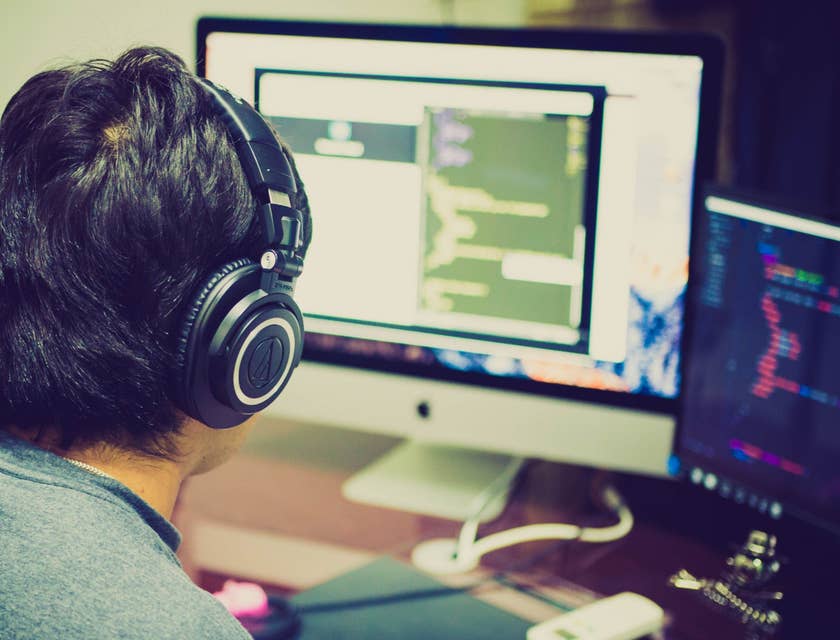 .NET Developer wearing a headset and typing a code in front of his workstation