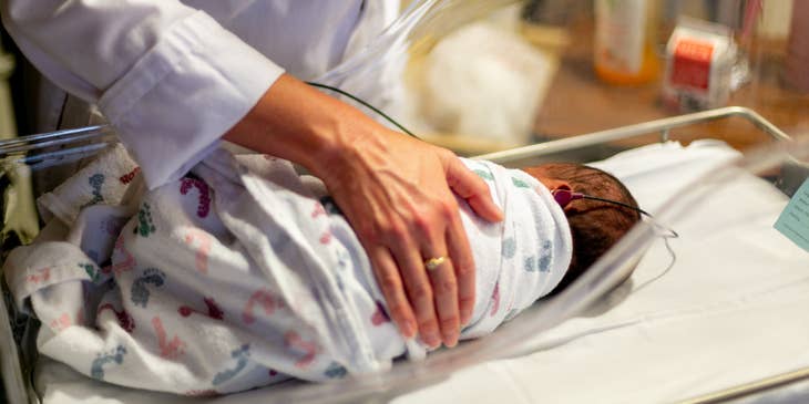 NICU nurse cares for the newborn on hearing test.