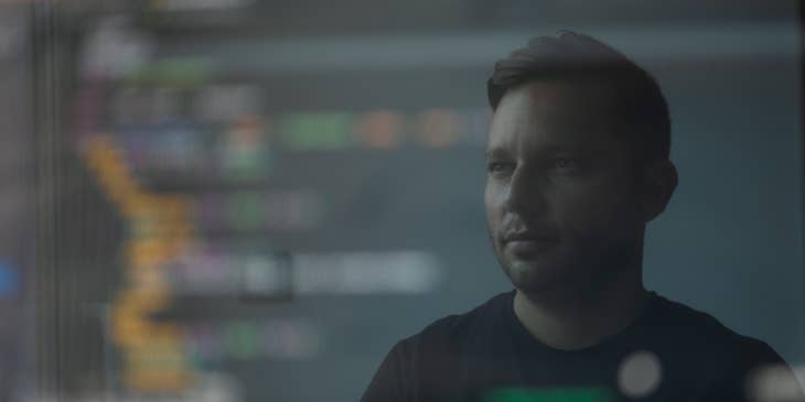 photo of a Node.js developer's reflection from his monitor while working on a program