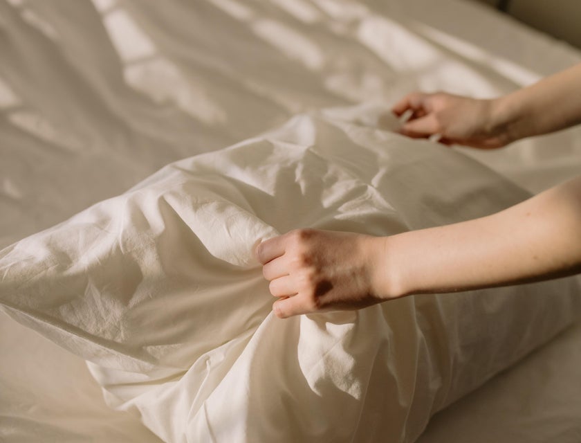 Nurse technician changes the bedsheet for the patient.