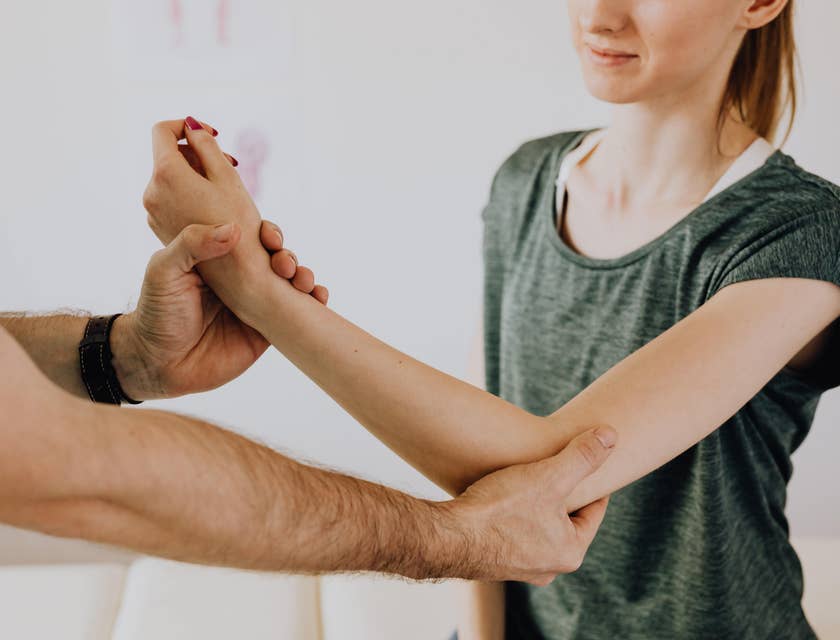 Occupational therapist assistant helping patient perform stretches.