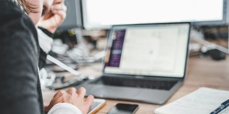 An operations analyst reading on a laptop.